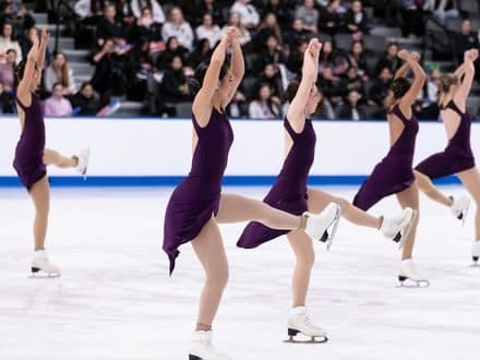 A line of skaters performing twizzles in unison