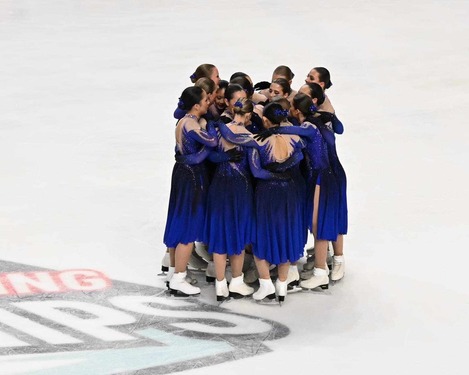 A Hayden Synchro team in blue dresses huddled together on the ice at the 2026 U.S. Synchronized Skating Championships